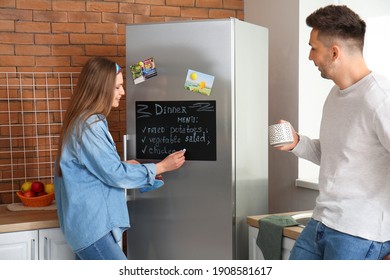 Young woman writing menu on chalkboard in kitchen - Powered by Shutterstock