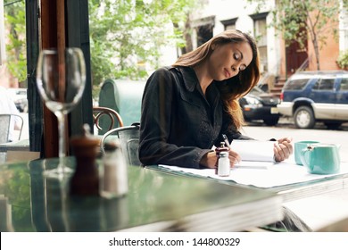 Young Woman Writing At Sidewalk Cafe