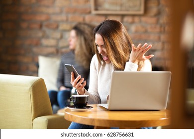 Young Woman Is Yelling On A Phone In A Cafe On Her Coffee Break