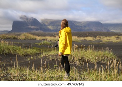 Young Woman With A Yellow Raincoat, Back Side, Icelandic Tundra. Iceland.