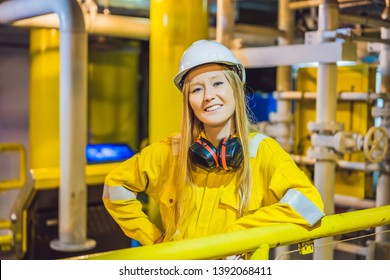 Young woman in a yellow work uniform, glasses and helmet in industrial environment,oil Platform or liquefied gas plant
