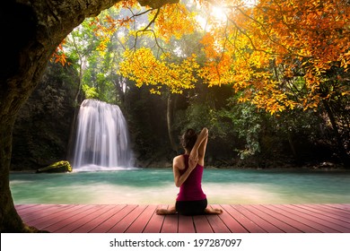 Young Woman In Yoga Cow Face Pose Sitting Near Waterfall, Rear View