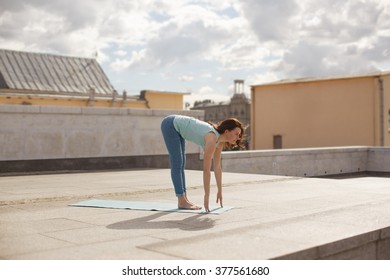 Young Woman In A Yoga Forward Bend Pose On The Roof