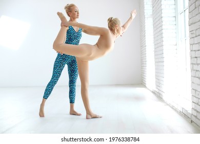 Young woman yoga instructor teaching postures, for a group of sports people practicing in the studio, training indoors, the teacher helps to master yoga. High quality photo. - Powered by Shutterstock