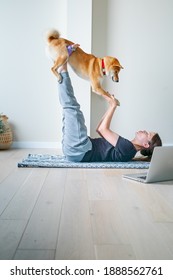 Young woman in yoga position balancing with her dog. Home online training with a pet. Doga or Doga yoga is the practice of yoga as exercise with dogs