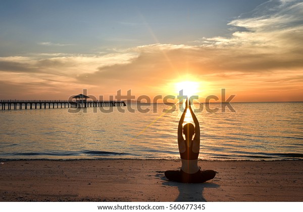 young woman yoga practice on the beach at sunset
