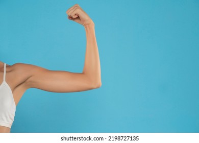 Young Woman's Bent Arm , Showing Bicep. Isolated On Blue Studio Background.