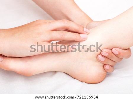 Young woman's foot joint being manipulated by osteopathic manual therapist or physician