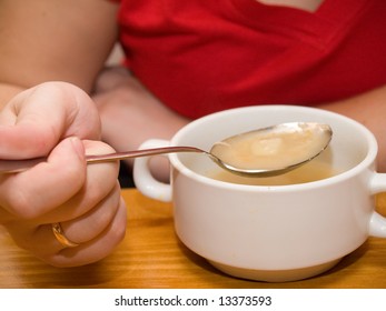 Young woman's hand with the spoon while eating fish soup in the restaurant