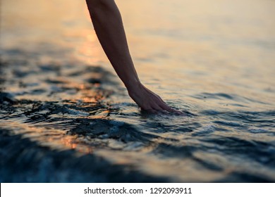 Young Woman's Hand Touching The Water In The Sea