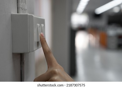 The young woman's hand turned off the light switch in the office. Energy saving concept. selective focus