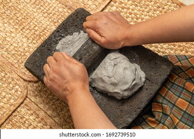 Young woman's hands, grinding dough in the metate for the elaboration of blue tortillas, which is a typical Mexican food, in the native towns the women are in charge of doing that task - Shutterstock ID 1692739510
