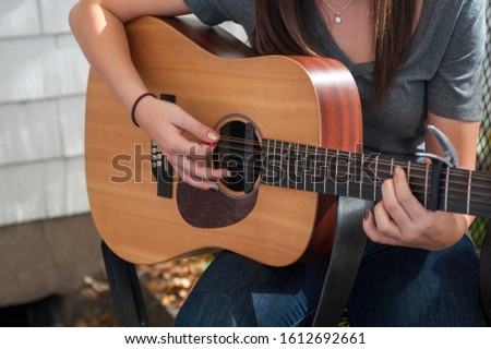 young womans hands strumming a 12 string acoustic guitar