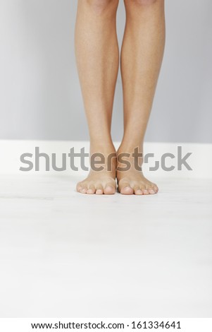Young woman's legs on wooden floor.