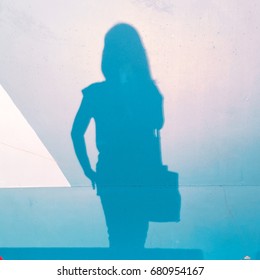 A young woman's shadow on a light blue wall in an afternoon