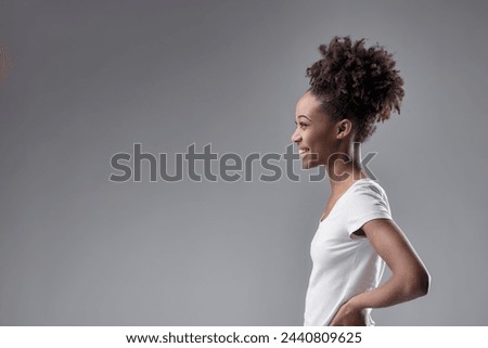young woman's side glance exudes confidence, with her natural hairstyle accentuating her character