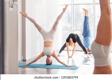 Young women are advanced yoga lovers do sarvangasana on rugs on the floor of the bright gym. Concept of improving blood supply to the brain and oxygenation of the chest
