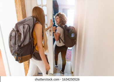 Young women with backpacks arriving to a youth hostel 