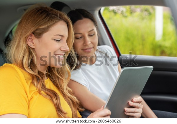 Young women in the car use the tablet. Girls with\
tablet pc in the car.