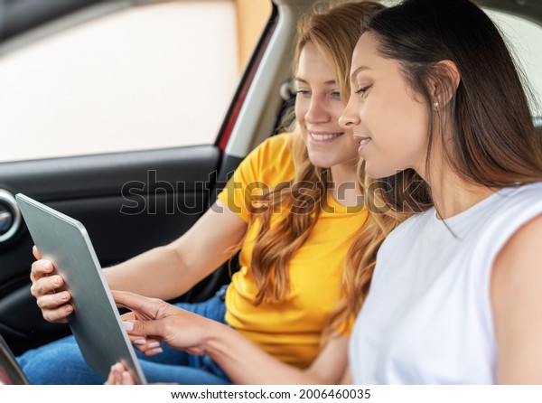 Young women in the car use the tablet. Girls with\
tablet pc in the car.