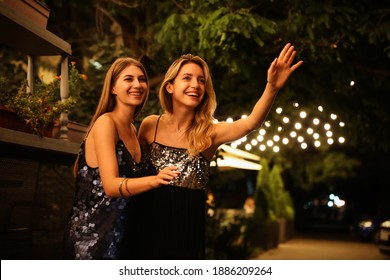 Young Women Catching Taxi On City Street At Night