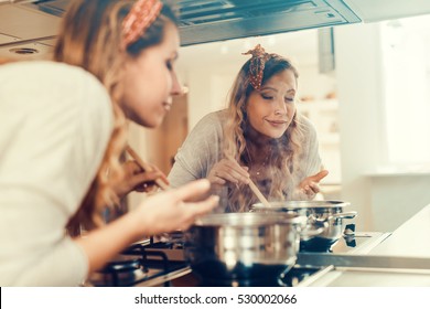 Young Women Cooking And Testing The Food In The Kitchen.