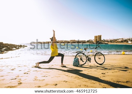 Young women is engaged in yoga on sunset with bike