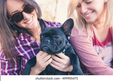 Young women enjoying outdoors with their adorable french bulldog. - Shutterstock ID 499905475