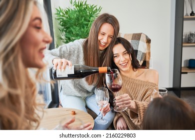 Young Women Enjoying Winter Weekends Inside Contemporary Barn House. Four Girls Having Fun And Drinking Wine.