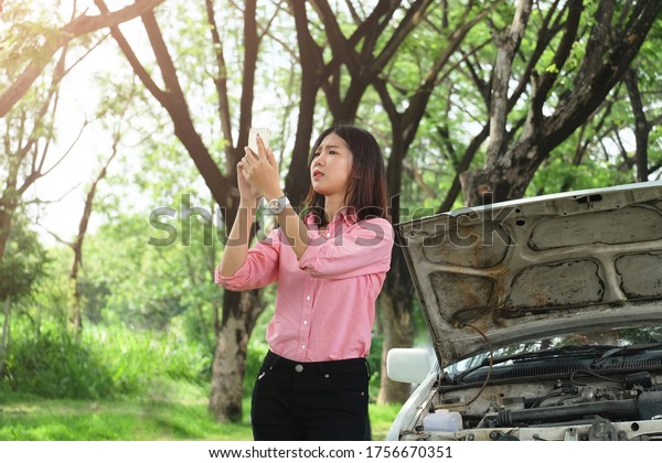 Young women find phone number of a car
mechanic.Asian lady stand near broken down old car and call for
help but no signal in country
area.