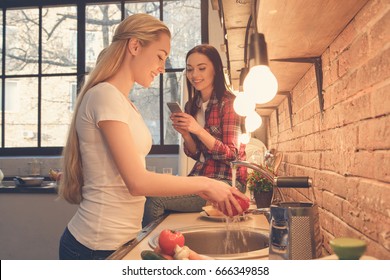 Young Women Friends Cooking Meal Together At Home