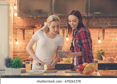 Young Women Friends Cooking Meal Together At Home