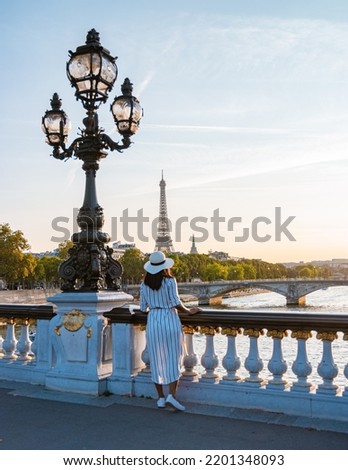 Young women with a hat viewing at the Eiffel tower from the Seine river, Alexander bridge Paris, view the famous landmark Alexander III bridge in Paris, the capital of France. 