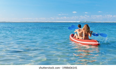 Young women have fun on boat walk. Girls paddling on kayak by sea lagoon. Travel lifestyle, recreational activity, watersports on summer beach family vacation.