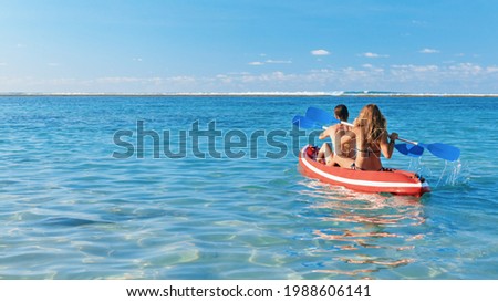 Young women have fun on boat walk. Girls paddling on kayak by sea lagoon. Travel lifestyle, recreational activity, watersports on summer beach family vacation.