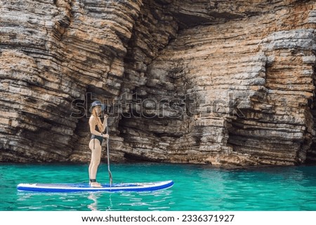 Young women Having Fun Stand Up Paddling in blue water seaamong the rocks in Montenegro. SUP