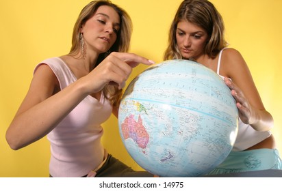 young women looking at globe