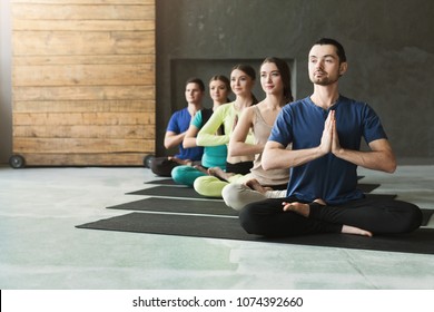 Young women and men in yoga class, meditation exercises. Lotus pose for relaxation. Healthy lifestyle in fitness club, crop, copy space, selective focus