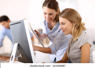 Young Women In Office Working Together On Desktop