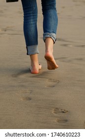 young women on the beach, foot prints on wet sand, footsteps on the beach, one person, feet and jeans, horizontal