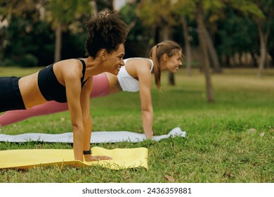 Young women outdoor in park standing in plank pose doing push ups or press ups exercise - Powered by Shutterstock