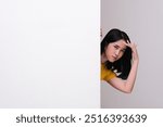 Young women peeking from behind wall with curious expression