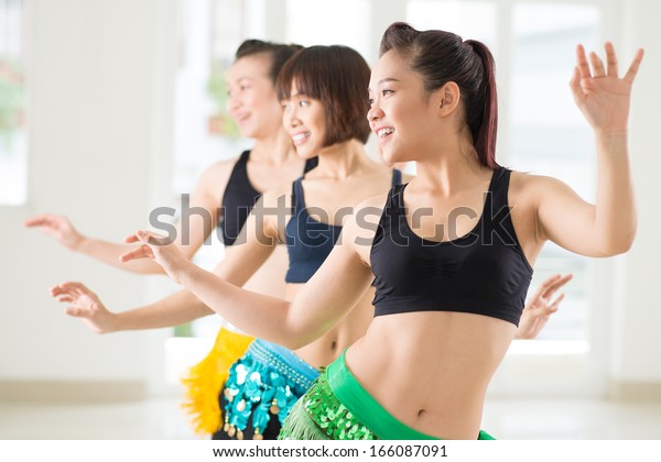 Young women performing belly dance in a dance\
studio on the foreground