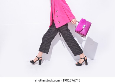 Young women in pink suit , fashion black striped pants with high hell shoes,holding pink handbag posing in studio