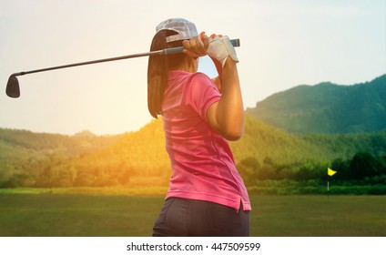 Young women player golf swing shot on course in morning sunrise
