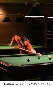 Young women playing billiard in club. Billiard room on the background.