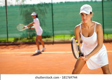 young women playing doubles at tennis at the tennis court