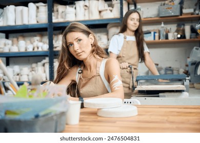 Young women potters sculpting clay products in workshop - Powered by Shutterstock