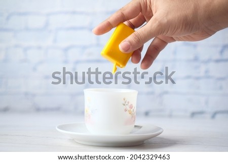 young women putting artificial sweetener in tea,