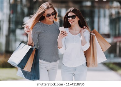 Young Women with Shopping Bags Walking City Street. Sale, Consumerism and People Concept. Shopping and Tourism Concept. Girls Bags Walking Down the Street on Sunny Day after Good Shopping.